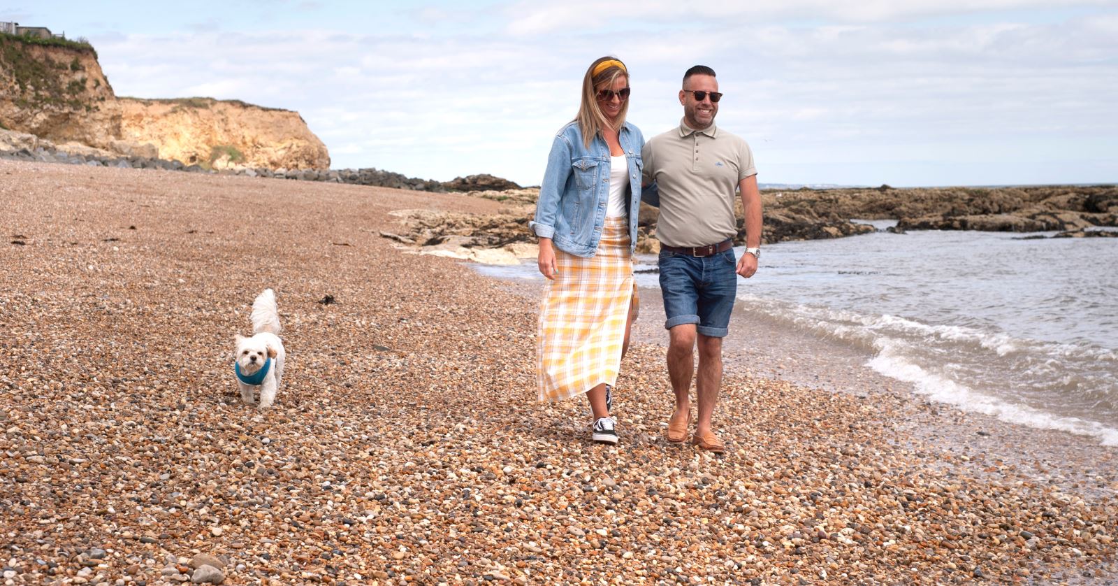 man and woman walking white dog on a beach in Durham